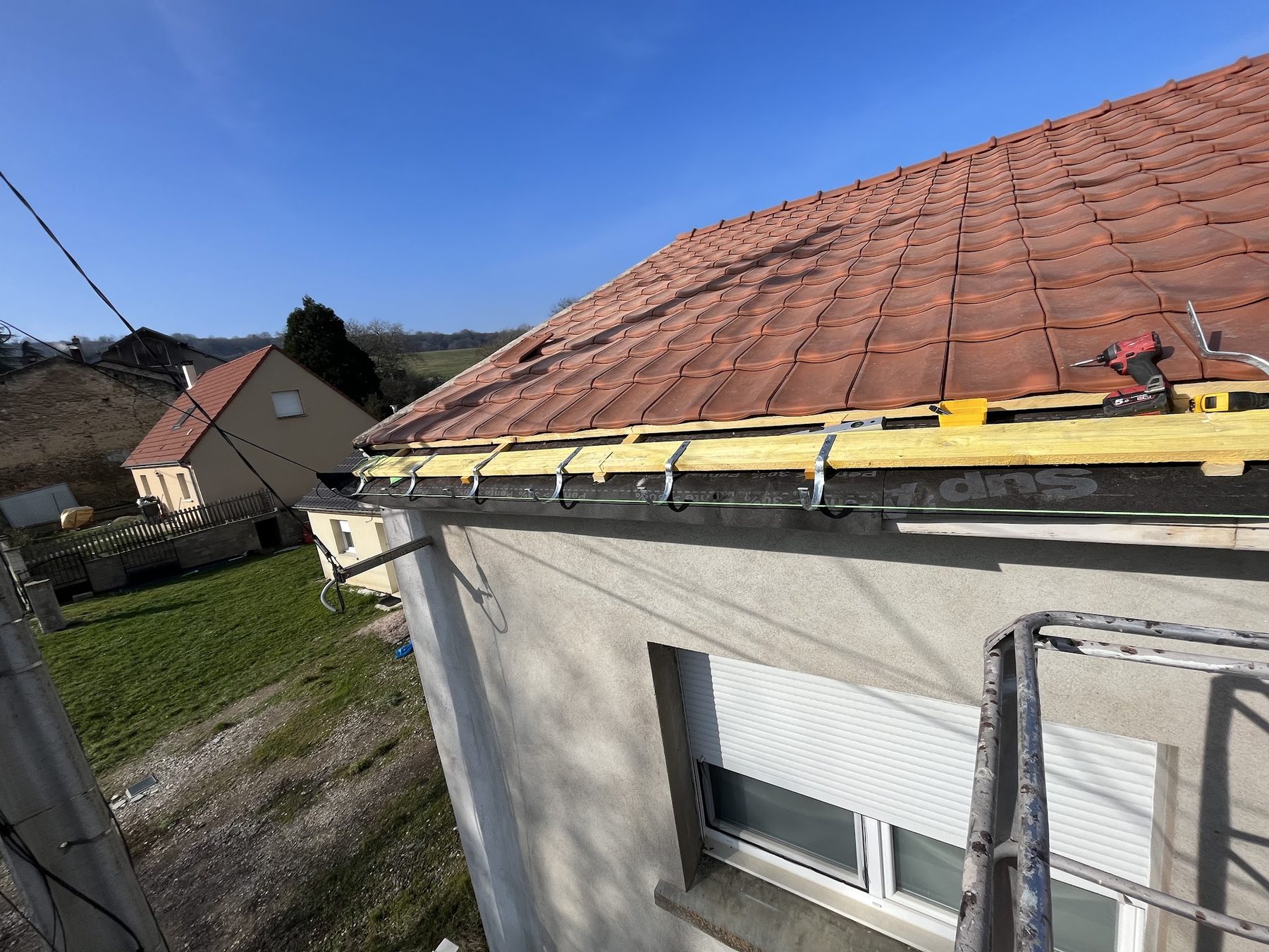 Tuiles rouges neuves en bas de pente avec crochets de gouttière